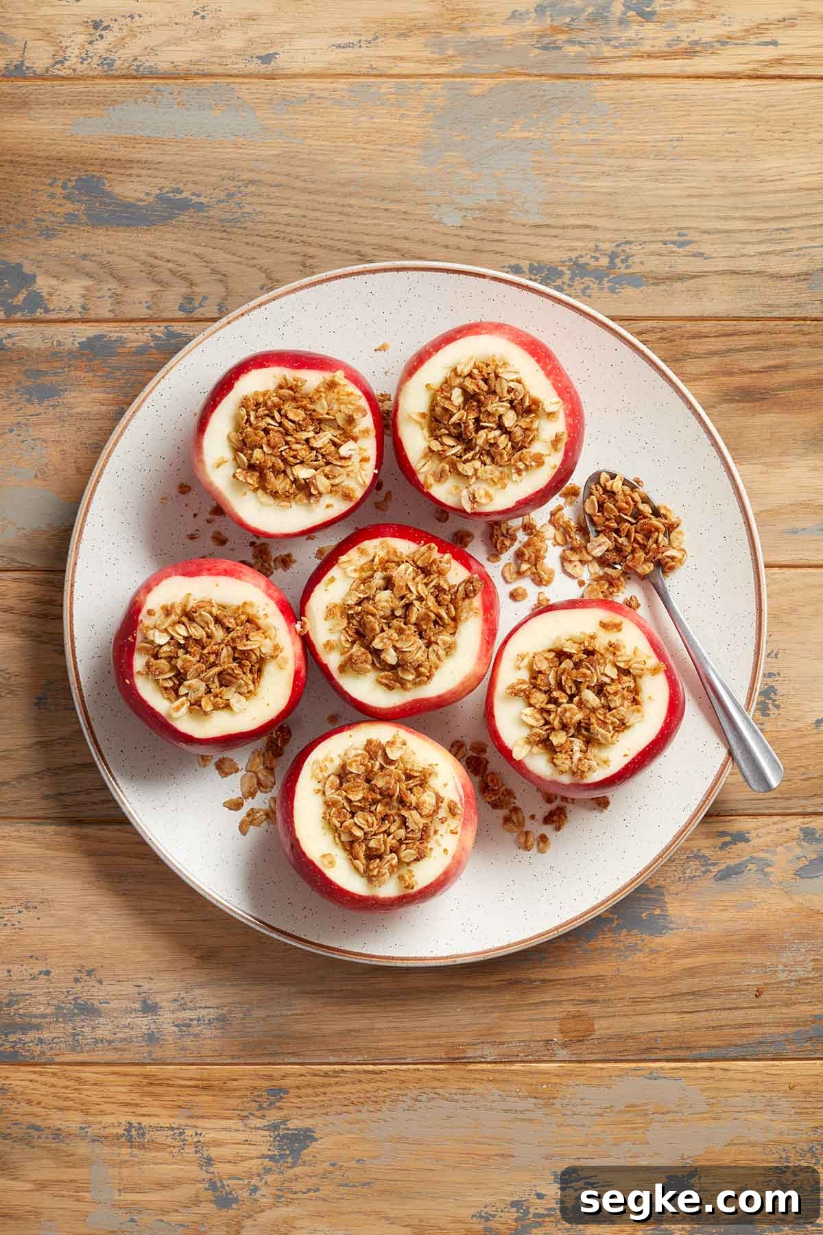 Six apples on a white plate and filled with cinnamon oat filling.