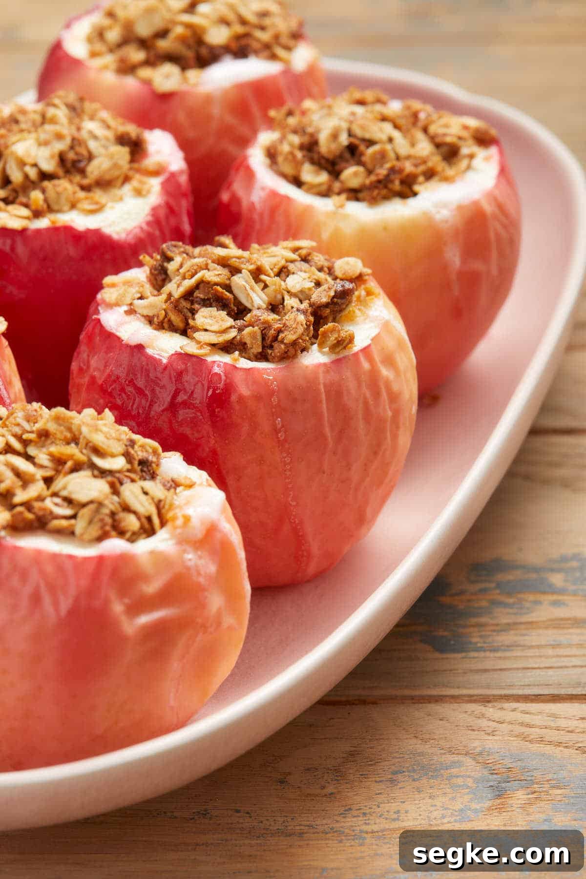 Side view of baked apples arranged on a pink platter.