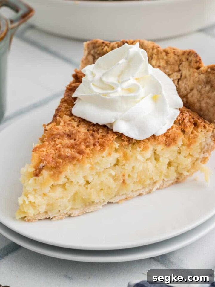 A slice of coconut pie with some cream squirted on top.