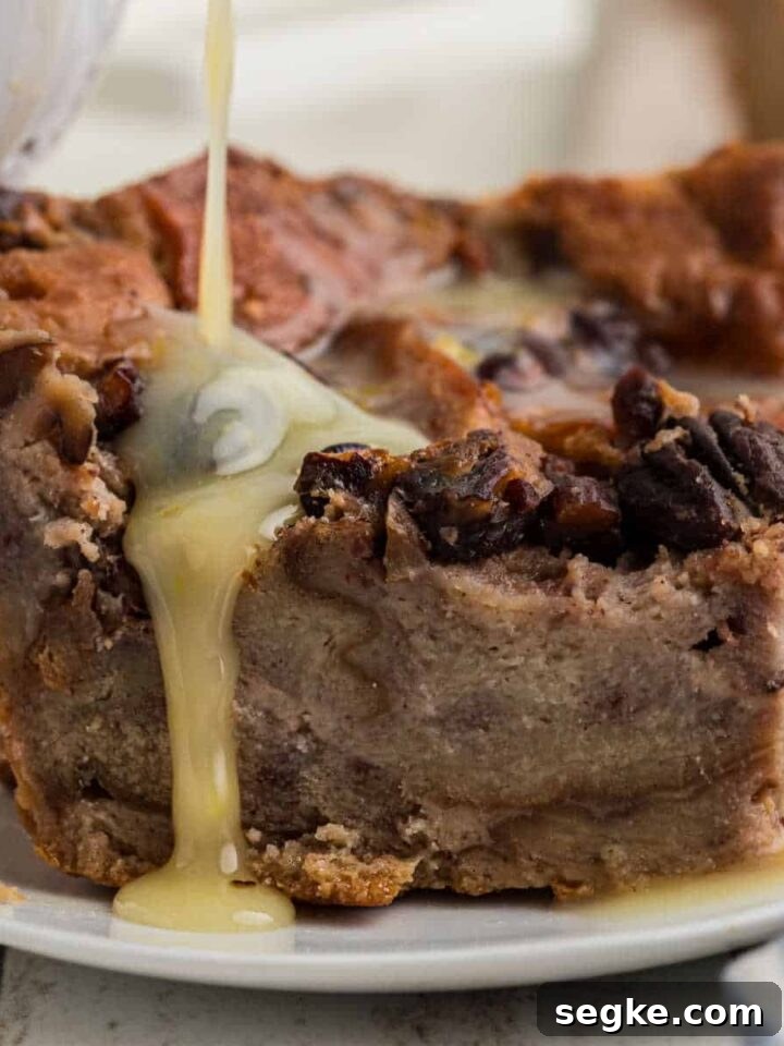 Rum sauce being poured over a slice of bread pudding.