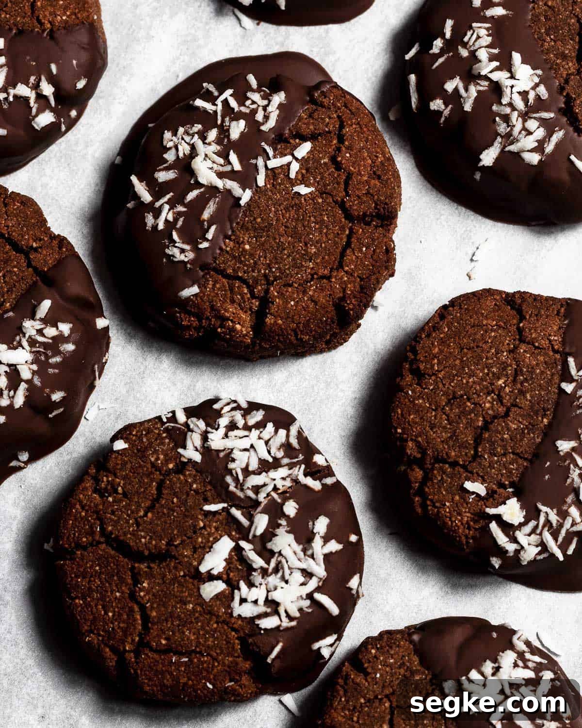 Gluten-Free Chocolate Coconut Biscuits Recipe 2 Chocolate Coconut Biscuits on a sheet of parchment paper photographed from above.