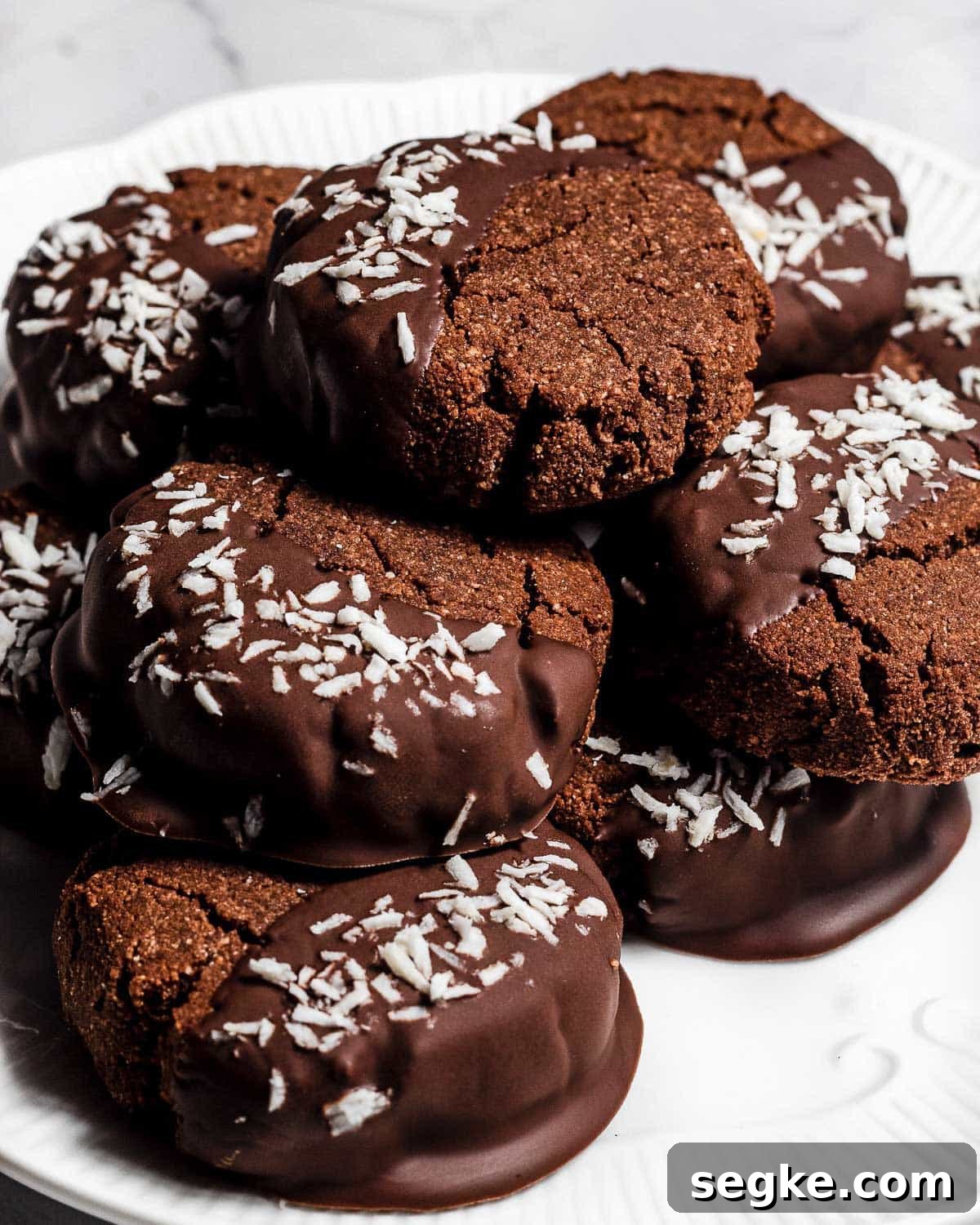 Gluten-Free Chocolate Coconut Biscuits Recipe 5 A pile of chocolate coconut biscuits on a white plate.