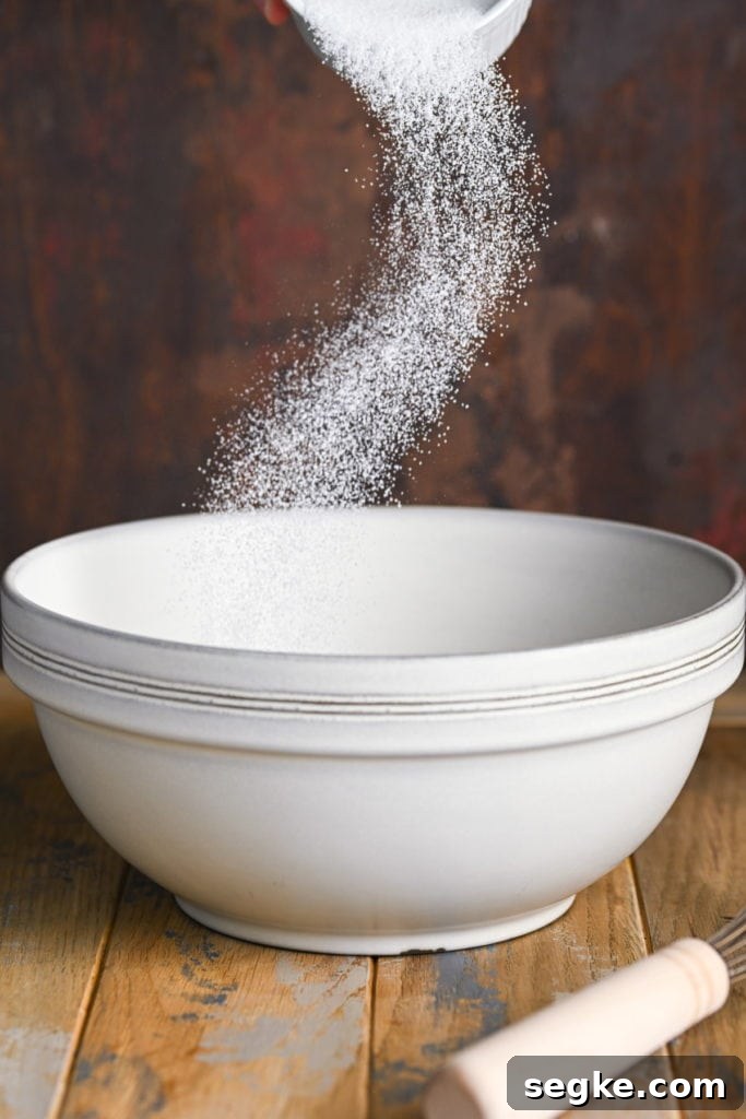 Adding sugar to oil to cream together to make muffin batter.