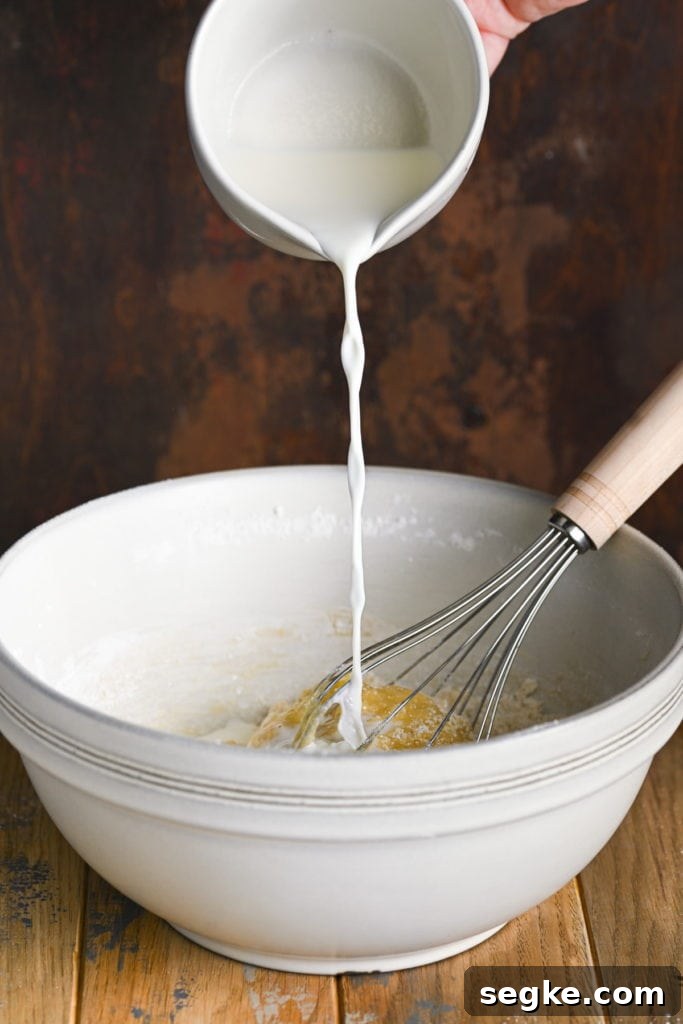 Adding milk to make moist blueberry chocolate chip muffin batter.