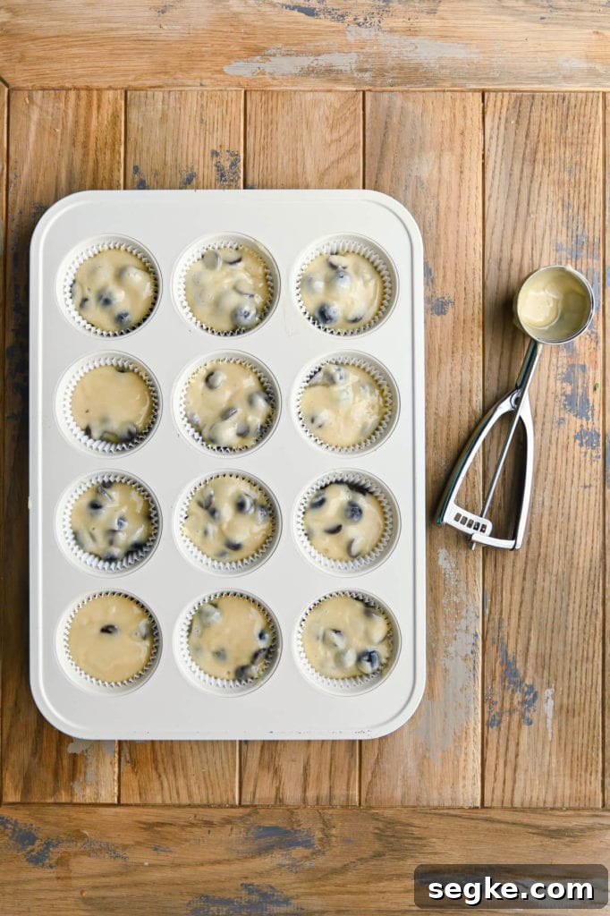 Adding batter to lined muffin tin.