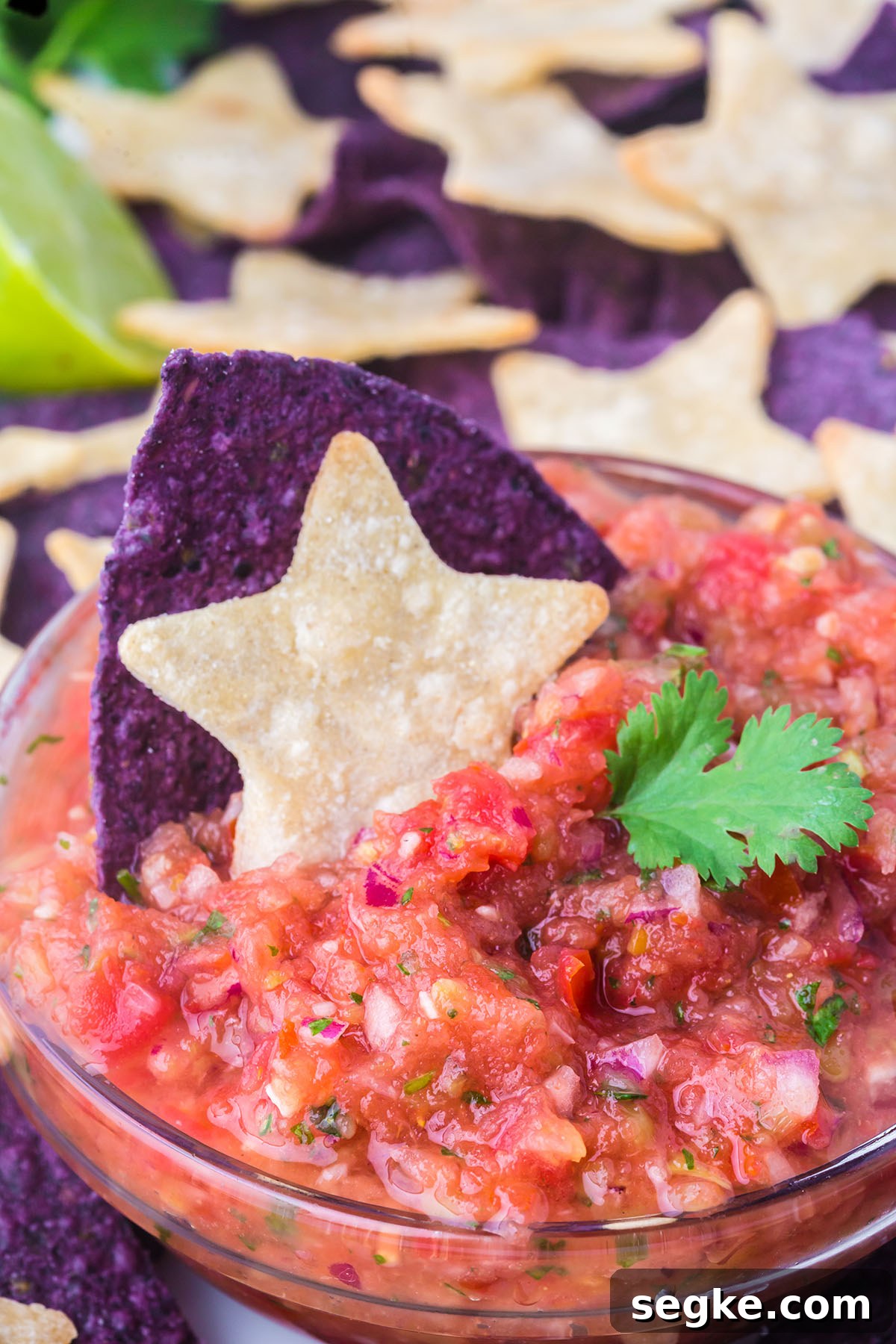 Salsa in a glass bowl with a star tortilla chip.
