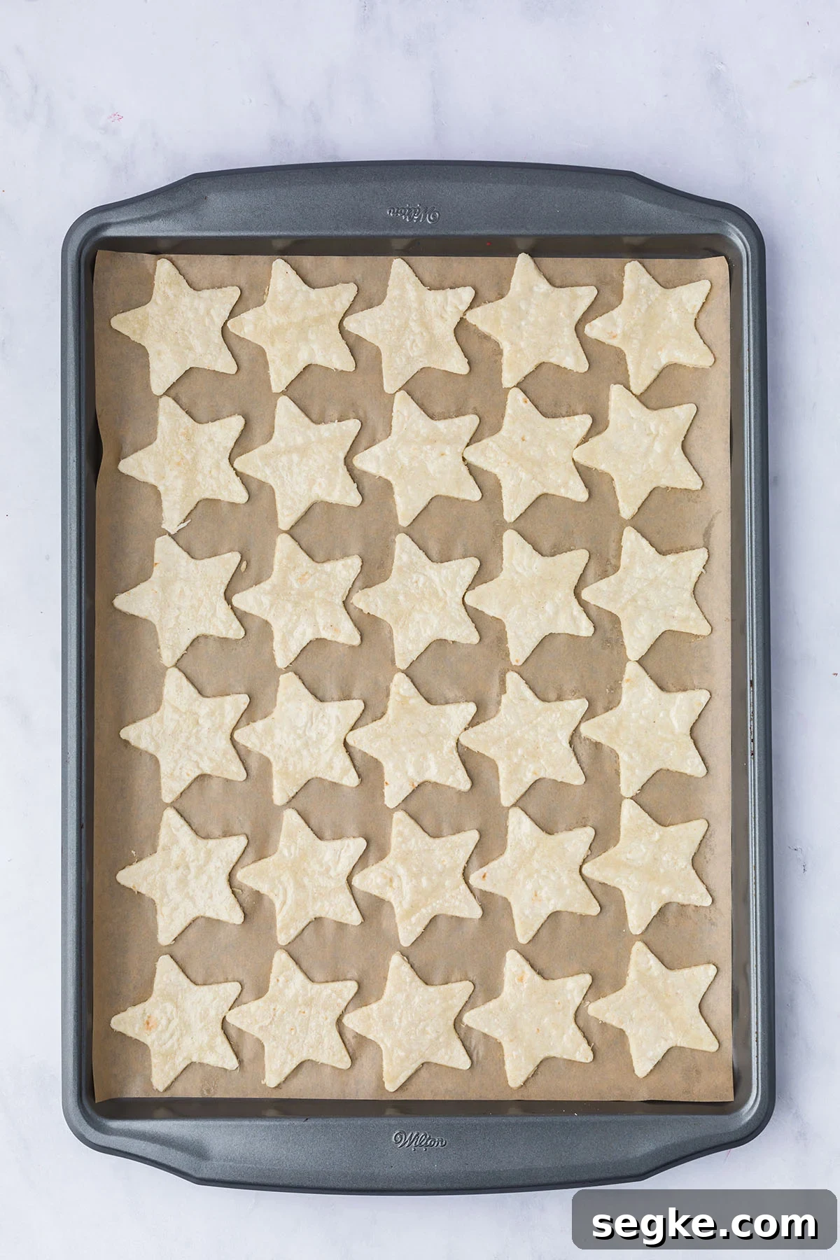 Star tortillas on a parchment paper lined baking pan.