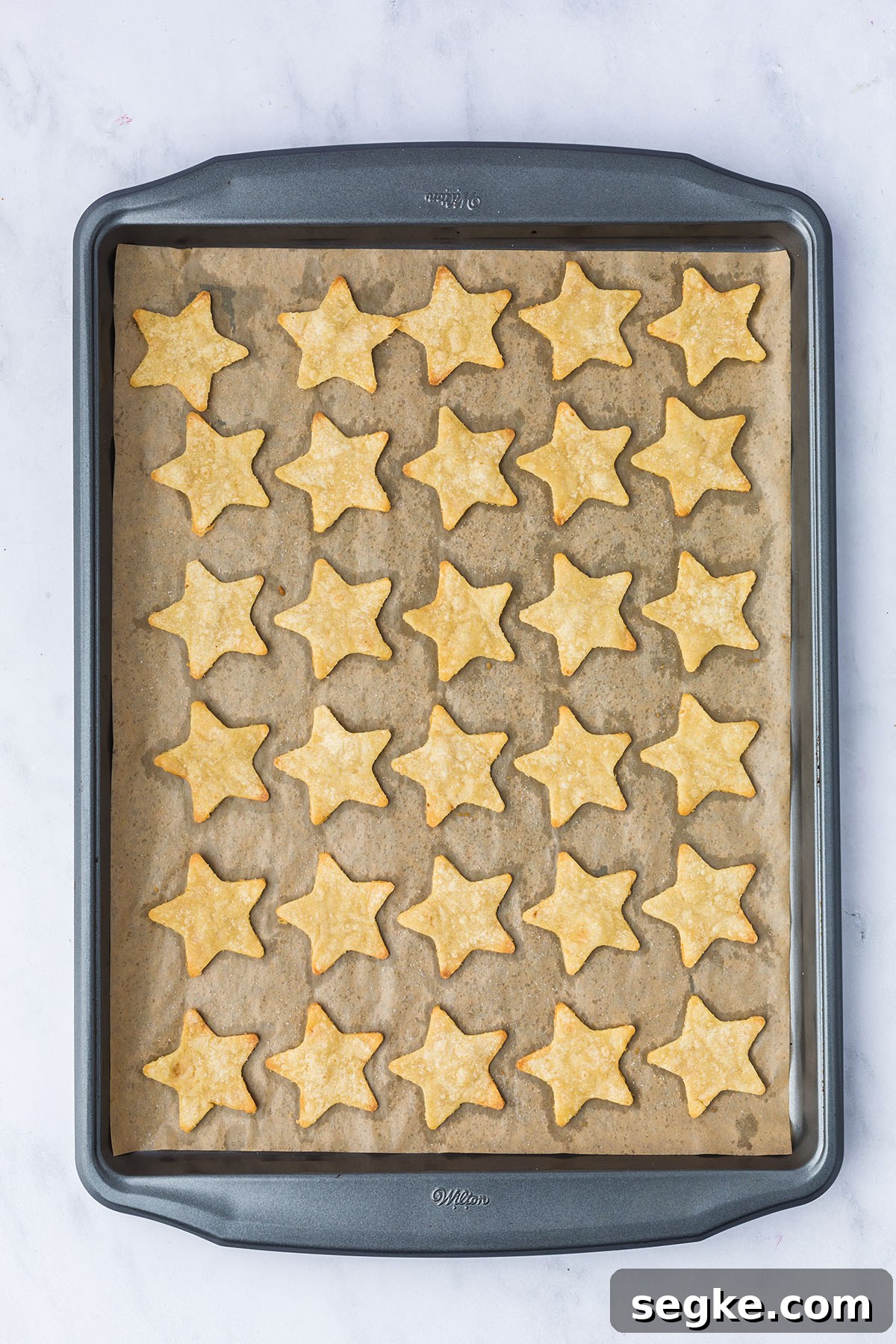 Baked star tortilla chips on a parchment paper lined baking sheet.