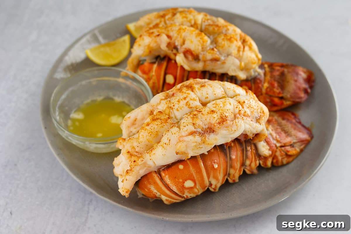 two broiled lobster tails with lemon and melted butter on the side.