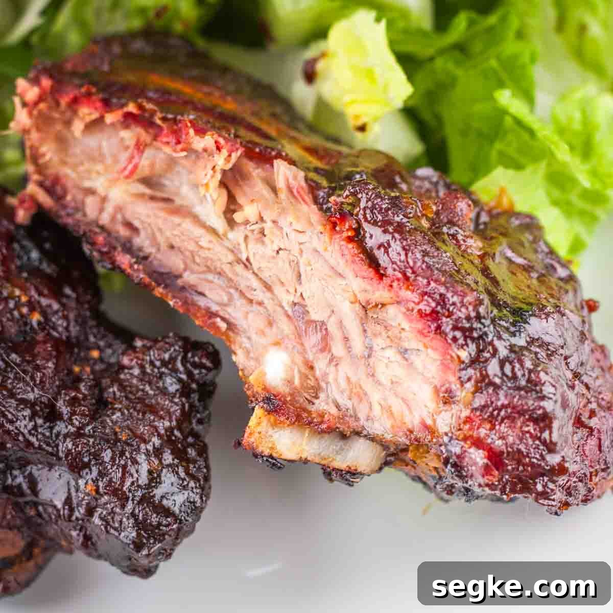 How to Smoke Beef Back Ribs on a Pellet Grill 16 Two smoked beef back ribs on a white plate with a green salad.