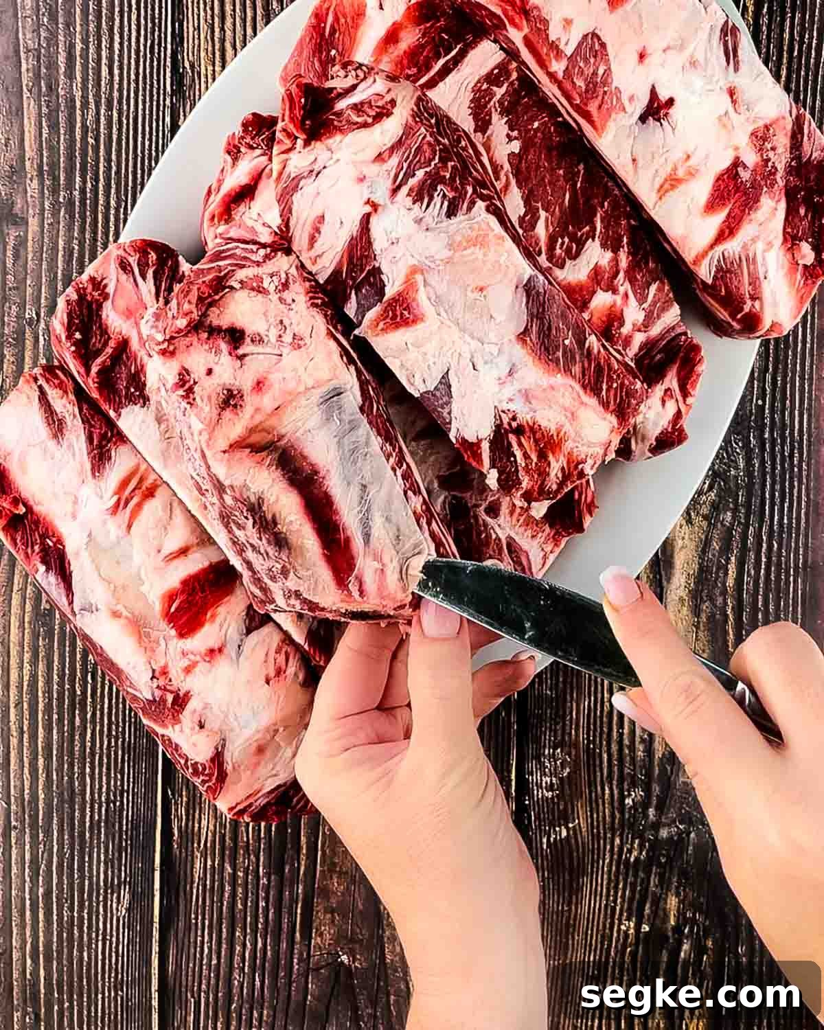 How to Smoke Beef Back Ribs on a Pellet Grill 3 A hand using a butter knife to get under the corner of the connective tissue on the back of the ribs.