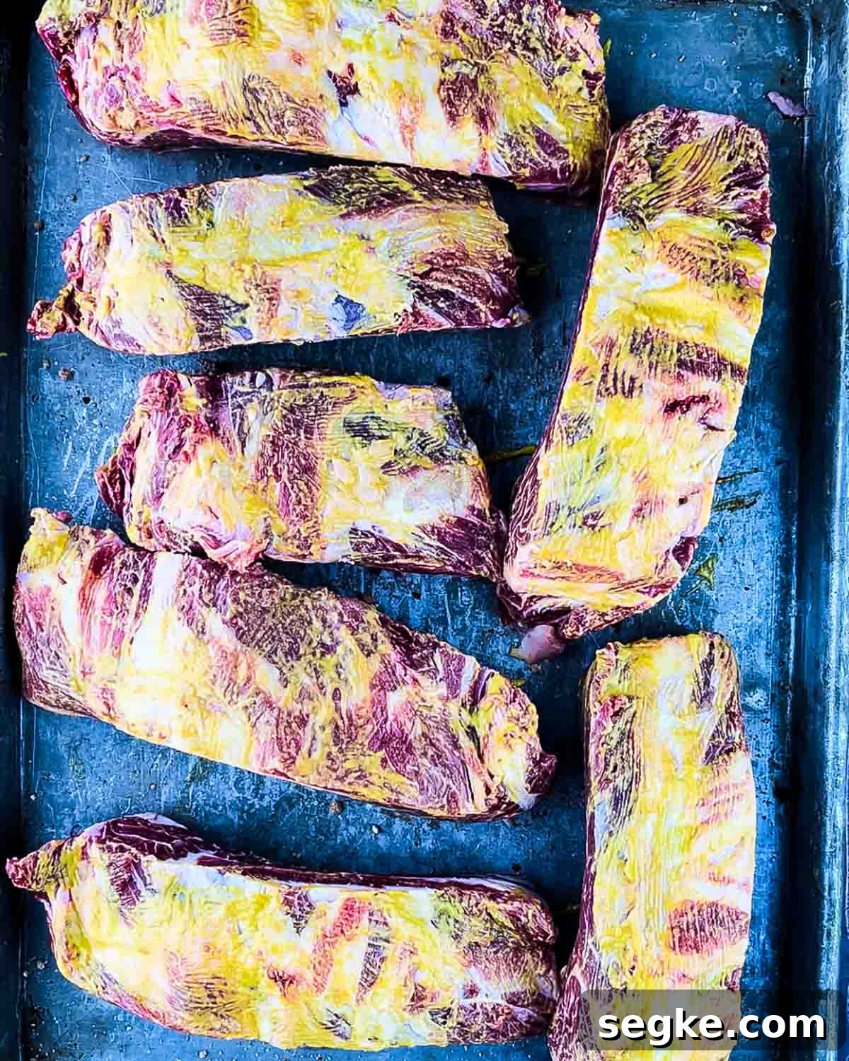 How to Smoke Beef Back Ribs on a Pellet Grill 7 The ribs on a baking sheet, brushed with yellow mustard.