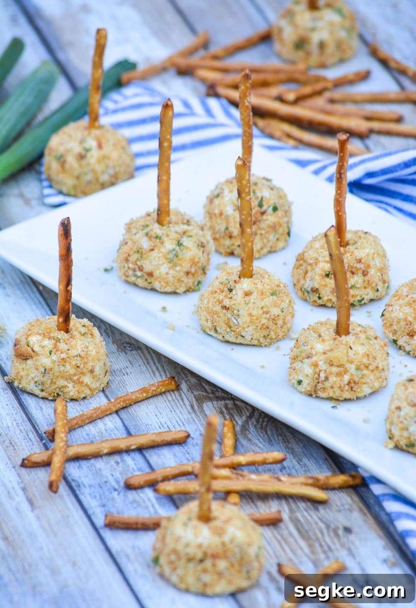 miniature cheese balls made with goat cheese arranged in two rows on a white platter