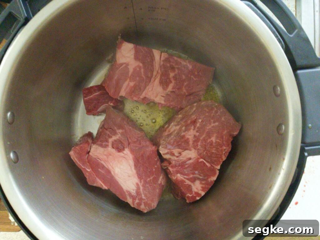 Instant Pot Mississippi Pot Roast Recipe (Juicy & Tender) 5 Pot roast in chunks being seared in instant pot for Mississippi pot roast. Step 2