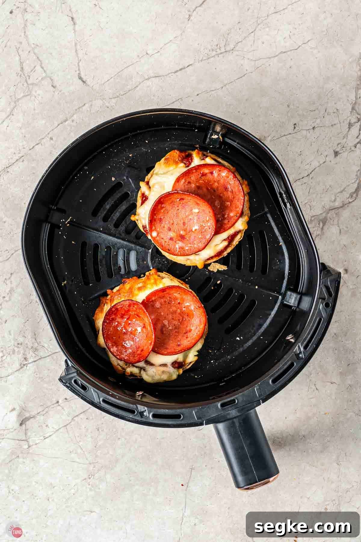 Crispy Air Fryer Pizza Bagels Recipe 7 bagels topped with pepperoni in an air fryer basket