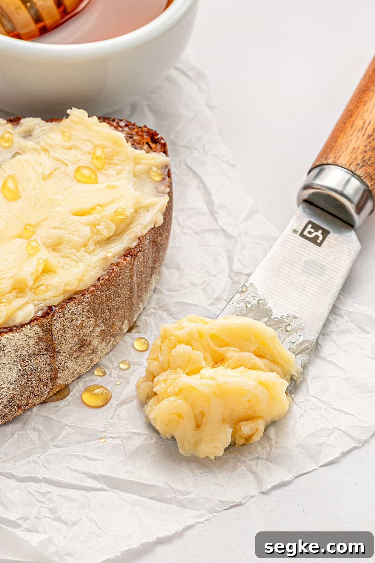 Whipped Honey Butter Recipe in 5 Minutes 3 Small knife and toast with honey butter. White paper surface.
