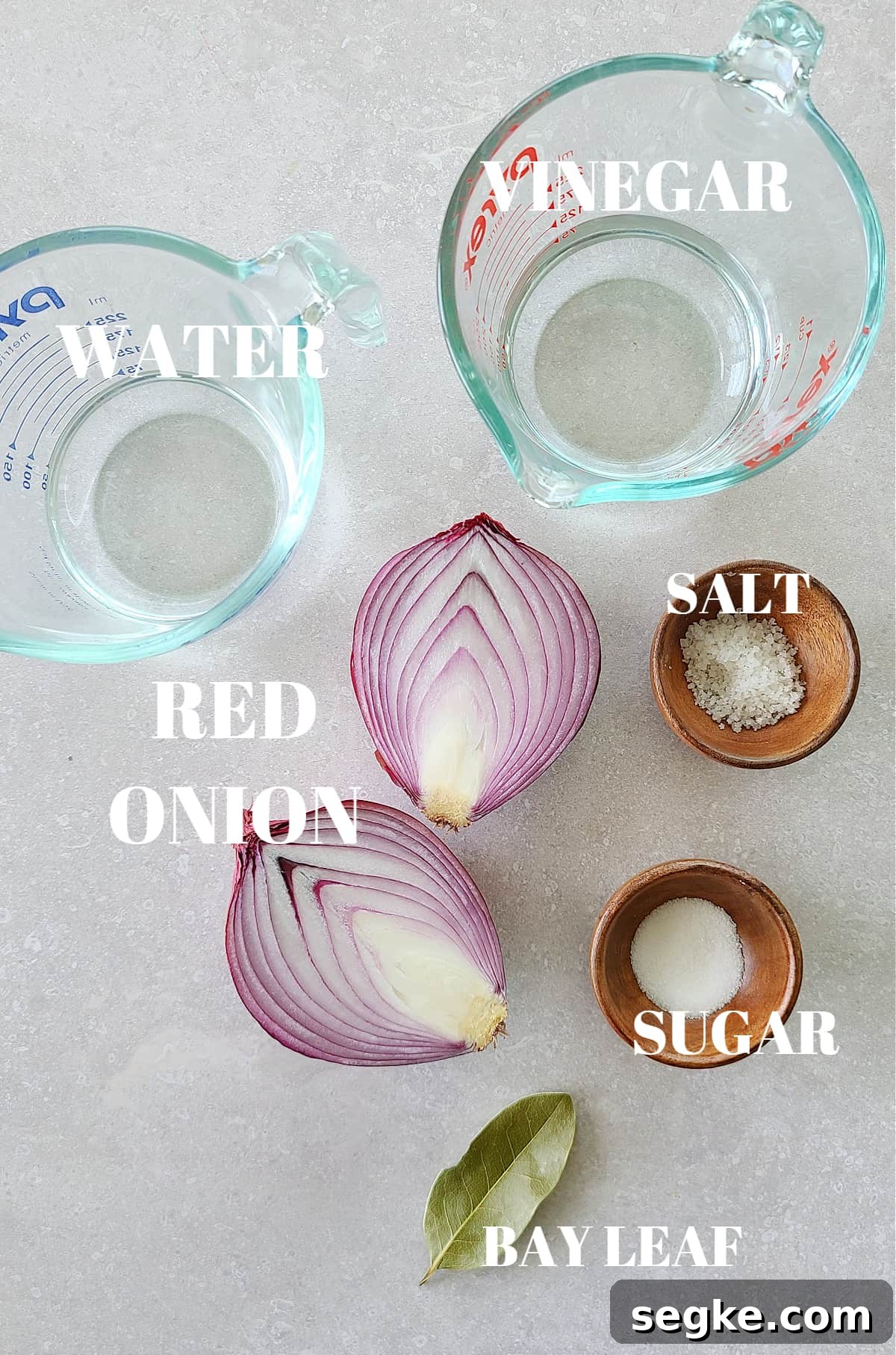 Ingredients for pickled red onions on a gray board.